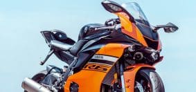 orange and black sports bike parked on gray concrete pavement during daytime