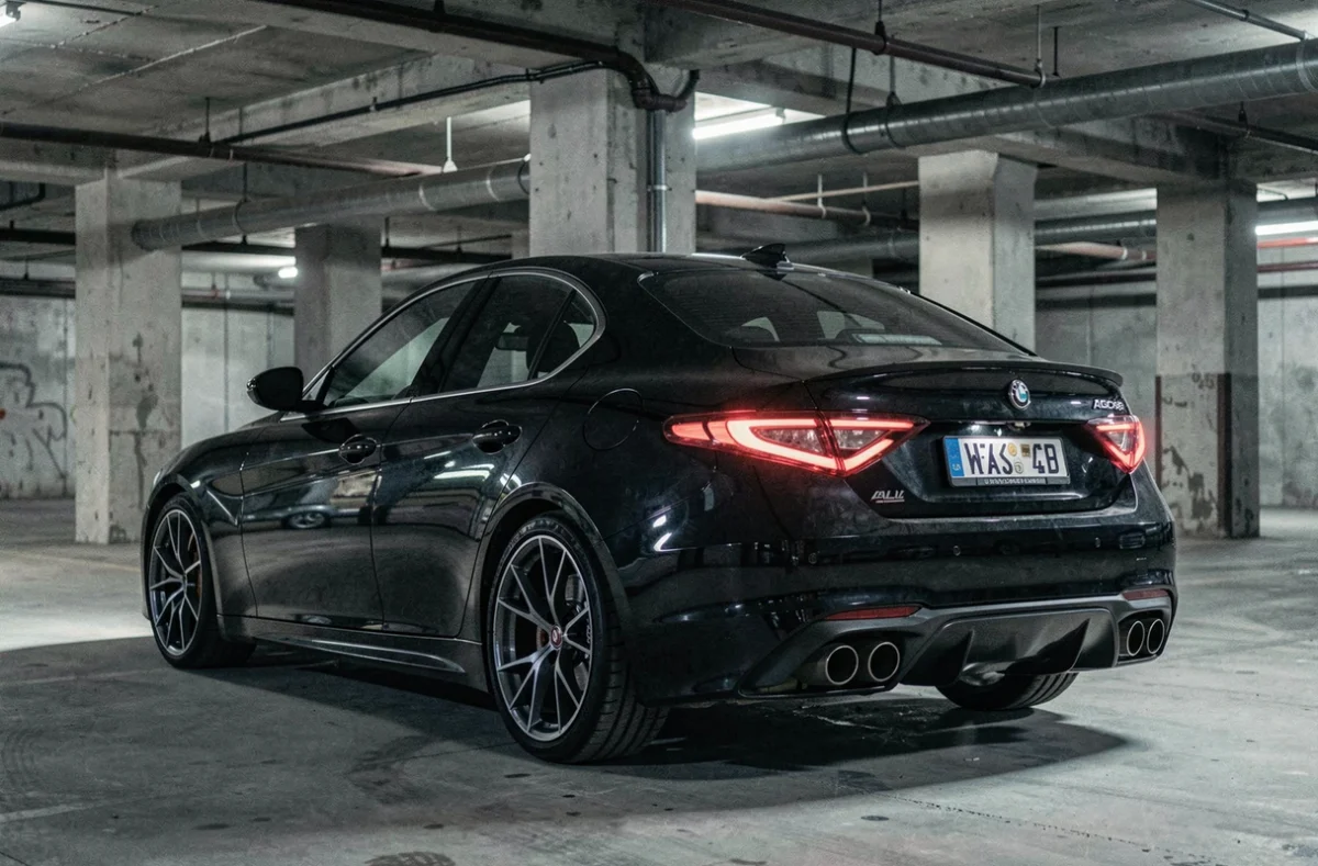 Alfa Romeo Giulia Quadrifoglio noire dans un décor de parking souterrain de studio cinématographique
