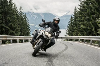 Motard en pleine courbe sur la route alpine près de Thonon-les-Bains avec vue sur le lac Léman en arrière-plan