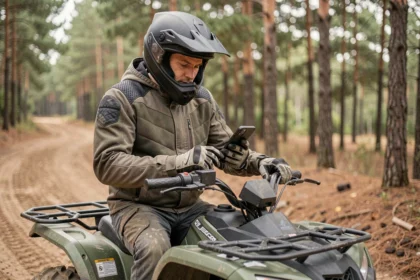 Motard assis sur un quad en forêt consultant son smartphone pour souscrire une assurance quad en ligne avant de partir
